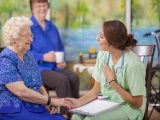 Медсестра проводит семейную консультацию с пожилой пациенткой и ее дочерьюв доме престарелых