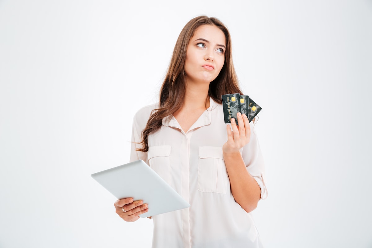 задумчивая женщина держит кредитную карту для пополнения счета 