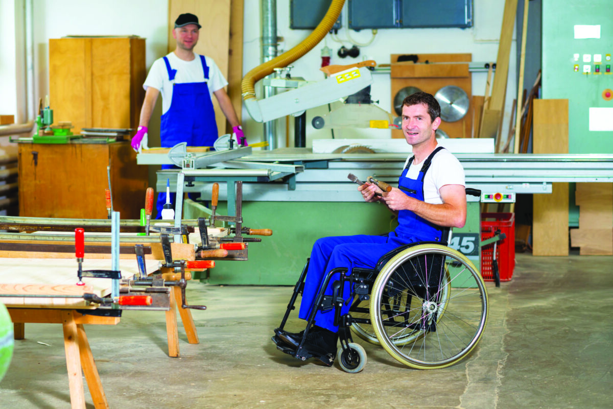 Чоловік в інвалідному візку в столярній майстерні зі своїм колегою